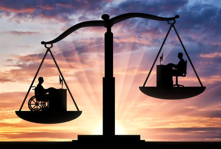 Silhouette of a worker disabled male in a wheelchair in priority over the employee healthy man on the scales of justice. The concept of people with disabilities the priority for employmentの写真素材