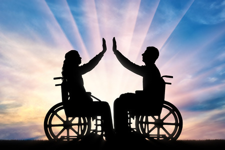 Silhouette of a woman and a man in a wheelchair, support each other. The concept of people with disabilitiesの写真素材