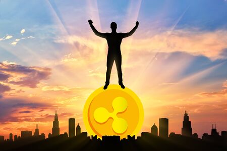 Happy man standing on a coin Ripple against the background of the city. The concept of success in the crypto currencyの写真素材