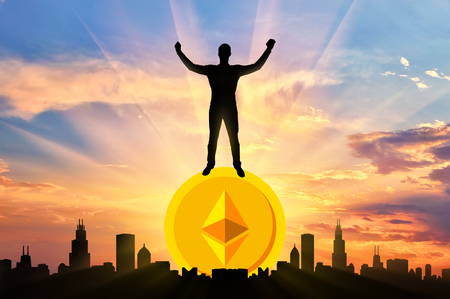 Happy man standing on a coin Ethereum against the background of the city. The concept of success in the crypto currencyの写真素材