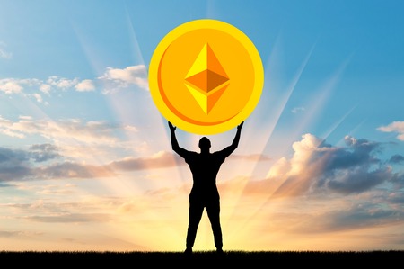 Silhouette of a man holding a coin ethereum against the sky. The concept of the future for crypto currencyの写真素材