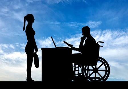 Silhouette of a man a businessman disabled in a wheelchair sitting at a table holds an interview with a woman about hiring a job. The concept of working disabled peopleの写真素材