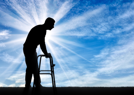 Silhouette of a disabled man walking, using a walker. The concept of rehabilitation of people with injuriesの写真素材