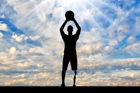 Silhouette of a disabled man with a leg prosthesis intends to throw a basketball ball. The concept of people with foot prosthesis and sportの写真素材