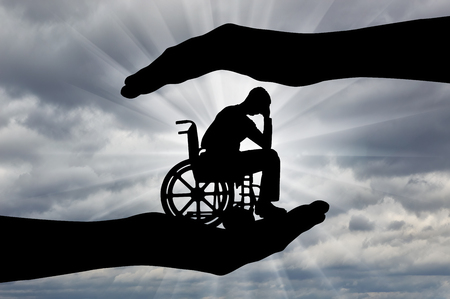 Silhouette of sad disabled man in wheelchair in hands of help.の写真素材