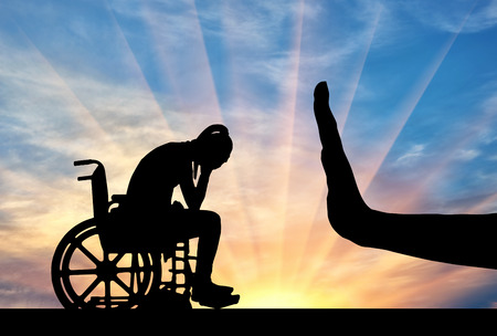 Silhouette of sad disabled woman in wheelchair and hand gesture stop. The concept of discrimination and disrespect for people with disabilitiesの写真素材
