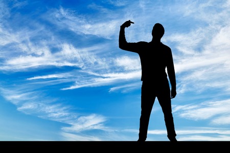 A silhouette of a narcissistic man shows his finger at himself. He tries to attract attention. The concept of narcissism and selfishnessの写真素材
