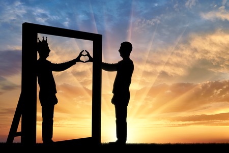 Silhouette of a narcissist man and hand gesture of a heart in reflection in the mirror and crown on his head. The concept of narcissism and selfishnessの写真素材