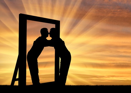 Silhouette of a narcissistic man hugging his reflection in a mirror. The concept of narcissism and selfishnessの写真素材
