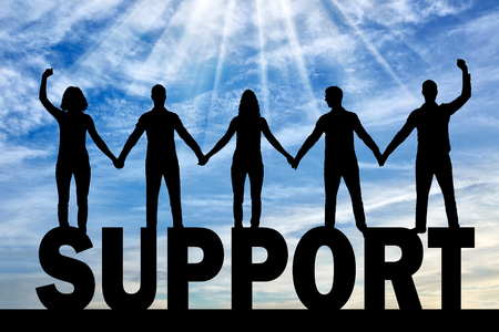 Silhouette of a group of happy people of five people holding hands while standing on a word of...