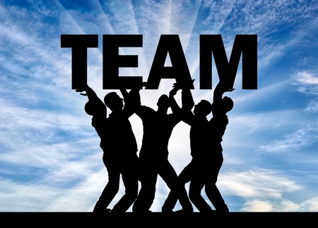 Silhouette of a group of men who hold the word team above themselves. The concept teamworkの写真素材