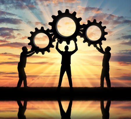 Silhouette of the three men holding the gears put them together in one gear. The concept of mutual aidの写真素材