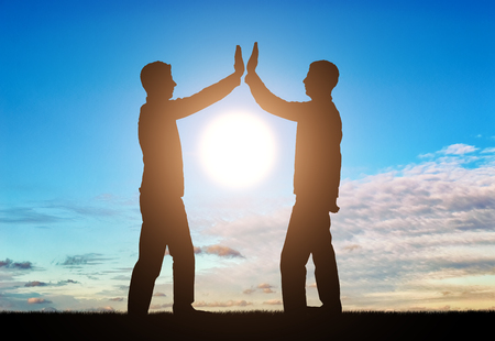 Silhouette of men make a gesture, give five. The concept of teamworkの写真素材