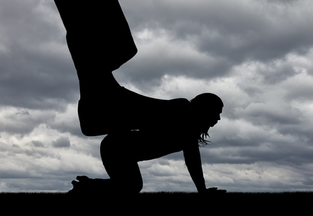 Silhouette of a large man's leg presses on a woman standing on all fours. The concept of discrimination and disrespect for womenの写真素材
