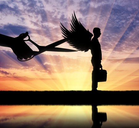Silhouette of a large hand with scissors intends to prune the wings of a man. Business conceptの写真素材