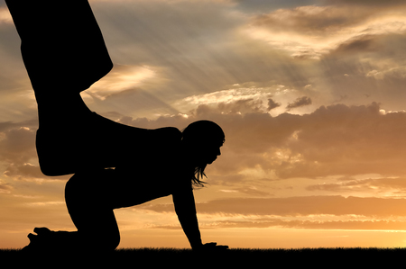 Silhouette of a large man's leg presses on a woman standing on all fours. The concept of discrimination against womenの写真素材