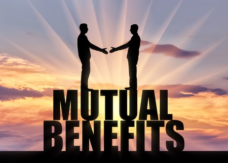 Silhouette two men are going to shake hands, standing on the word mutual benefit. Business concept of mutual benefitの写真素材