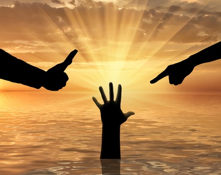 Silhouette of two hands, one shoots on video, and the other condemns the hand of a sinking person asking for help. The concept of a selfish society, a social problemの写真素材