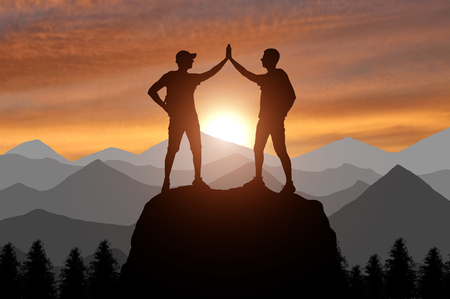 Silhouette of two happy climber conquered the top. A conceptual scene of success working in a teamの写真素材