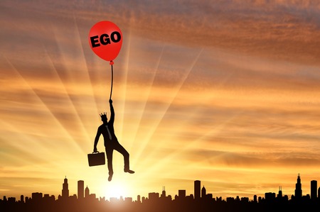 Selfish businessman holding on to a balloon called the ego soaring above the city. Conceptual scene...