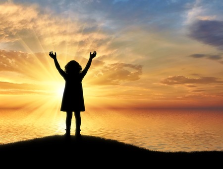 Silhouette, little happy baby girl standing on a hill near the sea on a background. Conceptual imageの写真素材