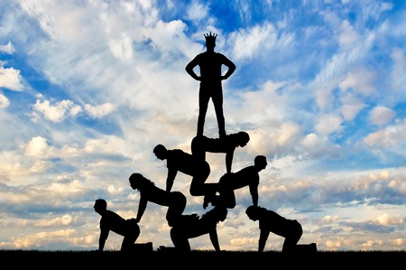 Silhouette narcissistic egoist man wearing a crown standing on humans. The concept of selfishness and narcissismの写真素材
