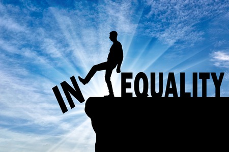 Man standing at the precipice pushes word inequality achieving equality of words. Concept of struggle with inequality in societyの写真素材
