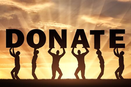 Altruism concept. Group of men holds the letters Donate on a sunset backgroundの写真素材