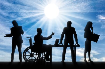 Disabled worker. Silhouette of a disabled man in a wheelchair. He likes to work with his work team.の写真素材