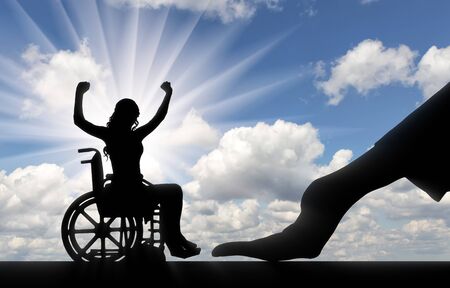 Disabled worker. Silhouette of a big hand of an employer hires a happy disabled woman in a wheelchairの写真素材