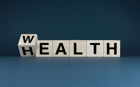Wealth - health. Cubes form words Wealth - health. Concept of balance and choice between health and wealthの写真素材
