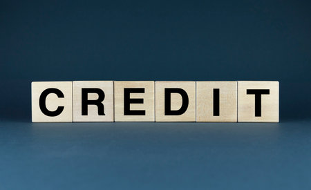 A minimalist composition featuring wooden blocks spelling the word CREDIT on a dark background. This image can be used to represent concepts such as finance, trust, and opportunity.の写真素材