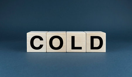 A minimalist composition featuring wooden blocks spelling the word COLD against a dark blue background.の写真素材