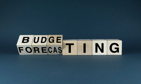 A conceptual image of wooden blocks spelling out the words 'budgeting' and 'forecasting'. This image represents financial planning, business strategy, and future-oriented thinkingの写真素材