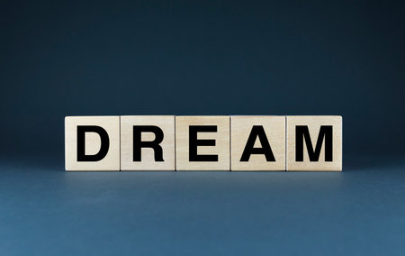 A minimalist image symbolizing the limitless potential of dreams. The word DREAM is spelled out on wooden blocks, representing the foundation of personal aspirations.の写真素材