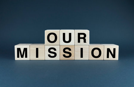 A conceptual image featuring wooden blocks spelling out the phrase 'Our Mission'. This image symbolizes unity, teamwork, and shared goals within an organization. Perfect for team-building activities, company cultural presentations, and motivational materialsの写真素材