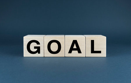 Wooden blocks spelling out the word GOAL against a dark blue background, symbolizing the pursuit of objectives and aspirations.の写真素材