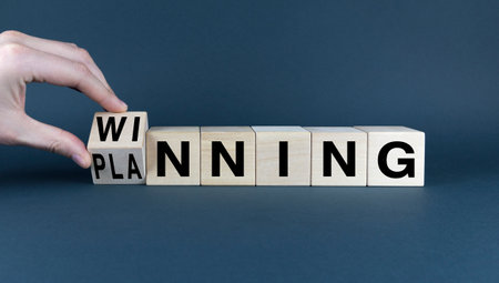 A conceptual image representing the idea of reaching goals through effective planning. A hand turns a wooden block to reveal the word 'winning', symbolizing the outcome of a well-executed strategyの写真素材