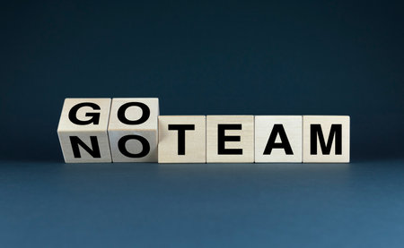 Wooden blocks spelling out GO TEAM and NOT TEAM, symbolizing the choice between teamwork and individualism. Perfect for illustrating concepts of motivation, decision-making, and personal growthの写真素材