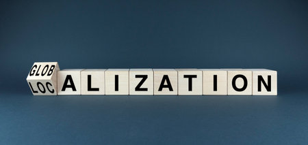 A wooden block with the word GLOBALIZATION is being flipped to reveal the word LOCALIZATION, symbolizing the balance between global and local perspectives in business and cultureの写真素材