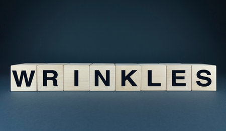 Wooden blocks spelling WRINKLES symbolize the natural aging process and the beauty of maturity. Ideal for illustrating articles, blog posts, or any project related to anti-aging and self-acceptanceの写真素材
