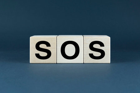 A closeup of wooden blocks spelling out SOS, a universal distress signal. This image can be used to represent emergency situations, danger, and the need for helpの写真素材