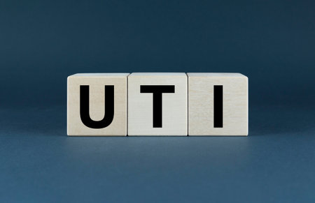 Wooden blocks spelling out the acronym UTI against a neutral background. The image emphasizes the importance of understanding and managing urinary tract infections for overall healthの写真素材