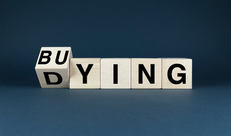 Blocks spell out BUYING with the first block tilted to reveal DYING. Concept business cycles, market volatility, and the importance of strategic planning.の写真素材