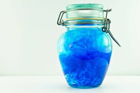 An antique jar full of water and blue colour with the lid closed.の写真素材