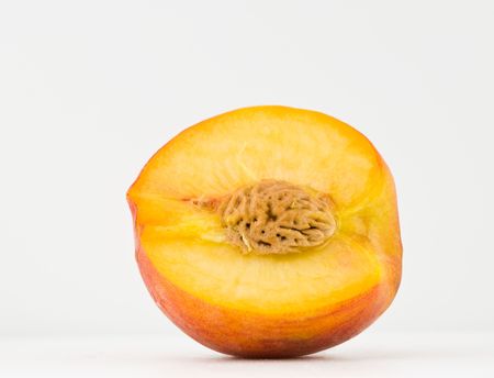 A fresh, ripe summer peach sliced open and isolated on white.の写真素材