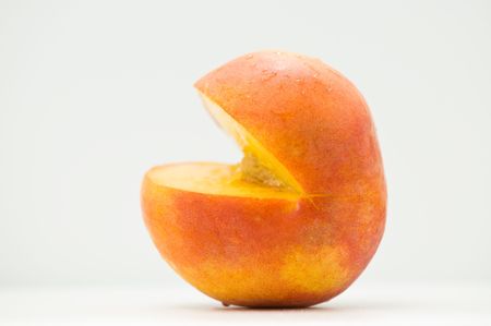 A ripe summer peach sliced sideways and isolated on white.の写真素材