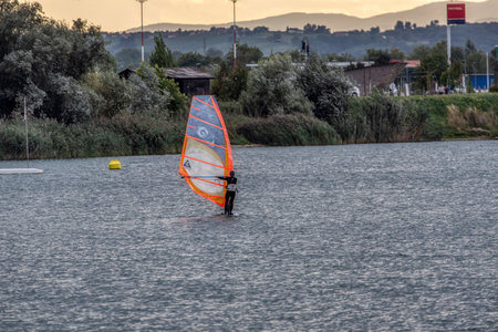 the man athlete rides the windsurf over the waves on lake in Murska Sobota, Prekmurje, Sloveniaの写真素材