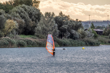 the man athlete rides the windsurf over the waves on lake in Murska Sobota, Prekmurje, Sloveniaの写真素材