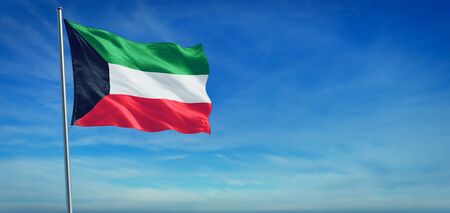 The National flag of Kuwait blowing in the wind in front of a clear blue skyの写真素材
